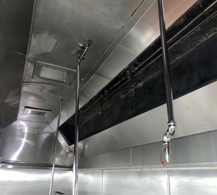 Clean fire suppression system nozzle and piping within a sanitized commercial kitchen exhaust hood.