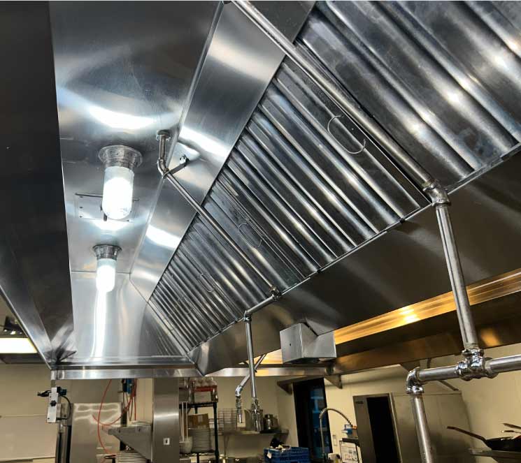 Pristine stainless steel commercial kitchen hood with clean baffle filters ensuring NFPA 96 compliance in San Diego.